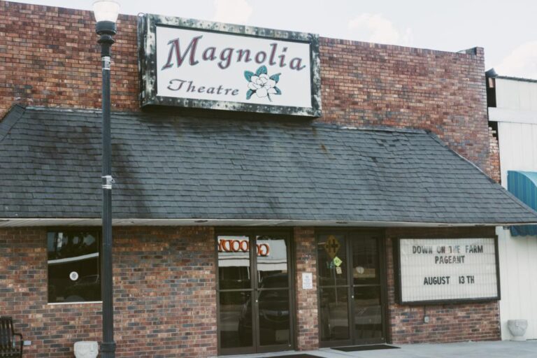 The brick facade and hanging sign of the Magnolia Theatre in downtown Eastman