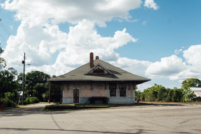 The historic Eastman railroad depot beneath a sky of tall summer clouds