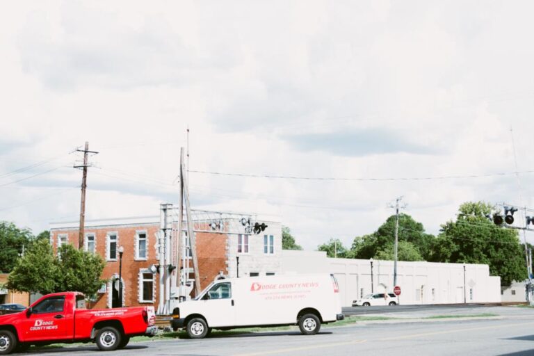 A city utility truck and pickup parked along a downtown Eastman street