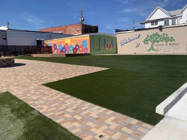 A green lawn and colourful murals at the downtown "Leave It Better" community park