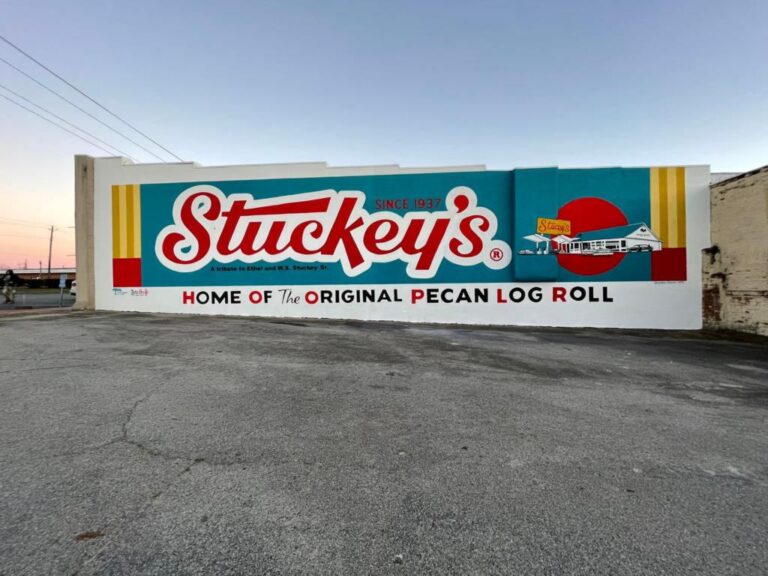 The Stuckey's mural reading "Home of the Original Pecan Log Roll" painted on a building wall at dusk